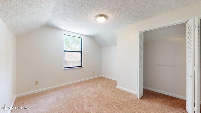additional living space with light carpet, lofted ceiling, a textured ceiling, and baseboards