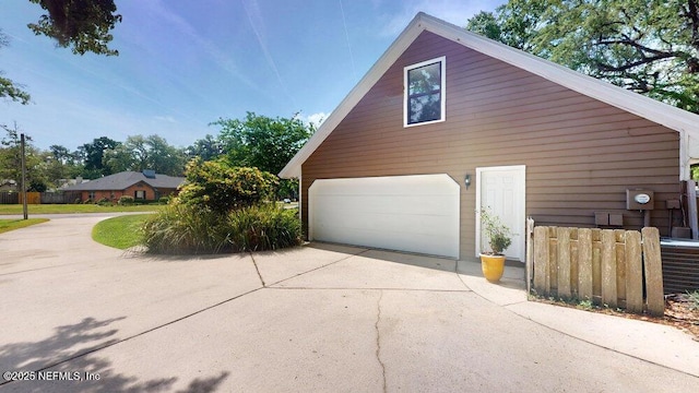 view of side of property featuring concrete driveway and fence