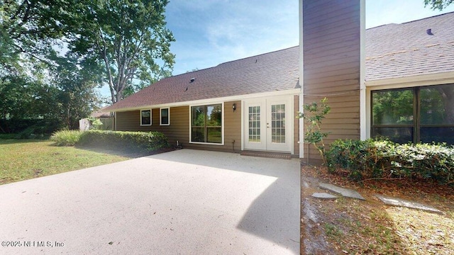 back of property with a patio area, french doors, a chimney, and roof with shingles