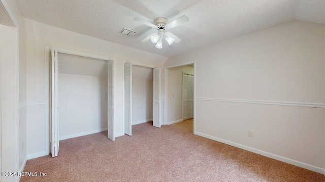 unfurnished bedroom with light colored carpet, baseboards, visible vents, and two closets