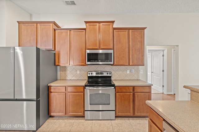 80 St Croix Island Dr, Saint Augustine, FL 32092 - kitchen with appliances with stainless steel finishes, light countertops, decorative backsplash, and light tile patterned flooring