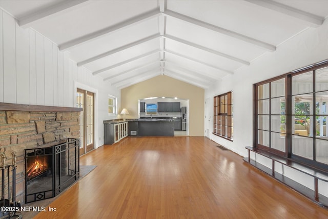 1800 N Halifax Ave, Daytona Beach, FL 32118 - unfurnished living room featuring light wood-style flooring, plenty of natural light, vaulted ceiling with beams, visible vents, and a stone fireplace