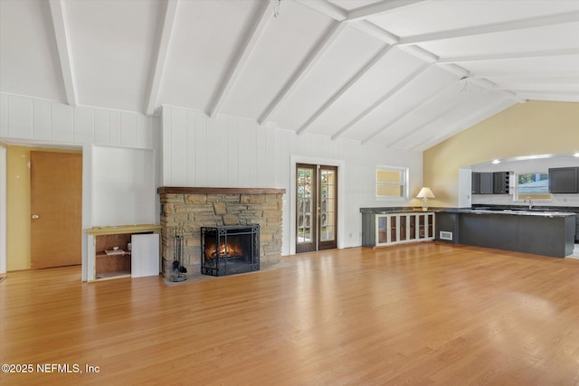 1800 N Halifax Ave, Daytona Beach, FL 32118 - unfurnished living room featuring lofted ceiling with beams, a sink, visible vents, light wood-style floors, and a stone fireplace
