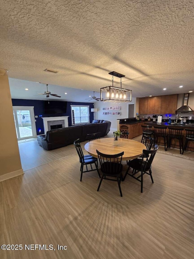 10 Quail Ln, Jacksonville Beach, FL 32250 - dining space featuring a textured ceiling, a tile fireplace, ceiling fan, and a wealth of natural light
