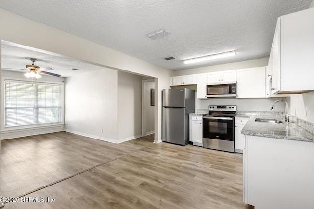 6504 Brandemere Rd S, Jacksonville, FL 32211 - kitchen with light stone counters, a textured ceiling, white cabinets, stainless steel appliances, and a sink