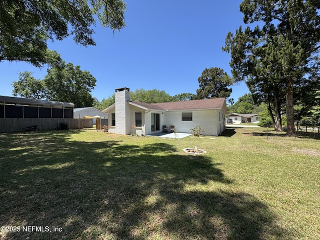 rear view of house featuring a yard, fence, a fire pit, and a chimney
