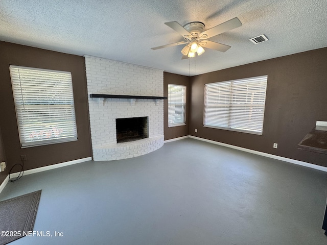 unfurnished living room featuring a brick fireplace, baseboards, a textured ceiling, and ceiling fan