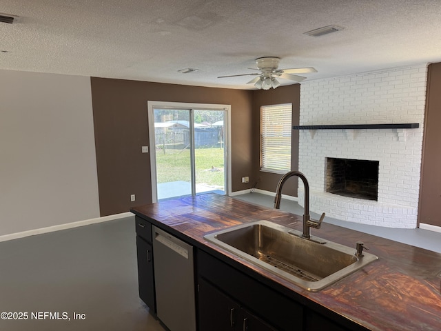 kitchen featuring a textured ceiling, dishwasher, a sink, and visible vents