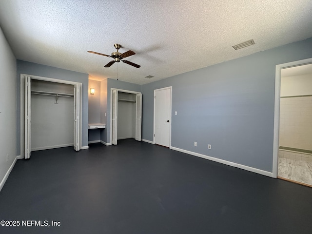unfurnished bedroom featuring baseboards, a textured ceiling, visible vents, multiple closets, and ceiling fan