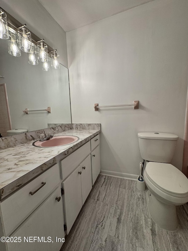 bathroom with vanity, baseboards, and toilet