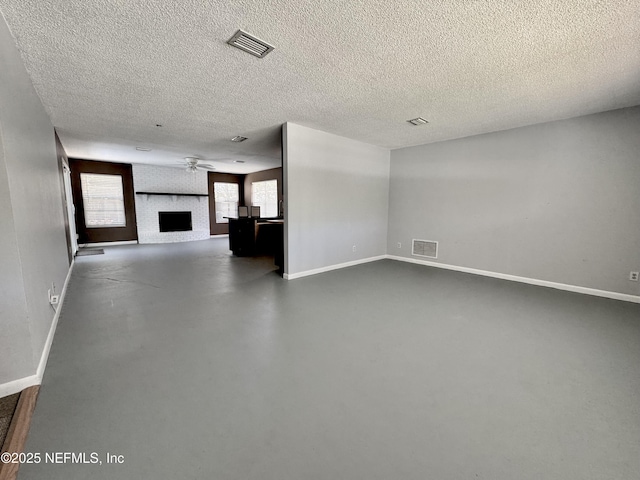 unfurnished living room with visible vents, baseboards, a textured ceiling, and ceiling fan