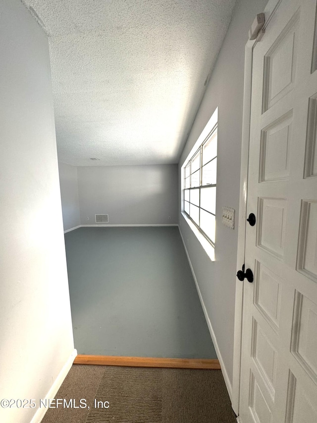 bonus room featuring a textured ceiling, carpet flooring, baseboards, and visible vents