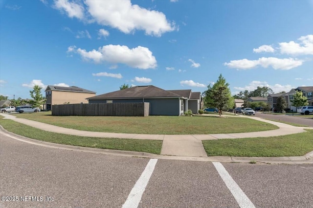 view of side of property featuring a residential view, a lawn, and fence