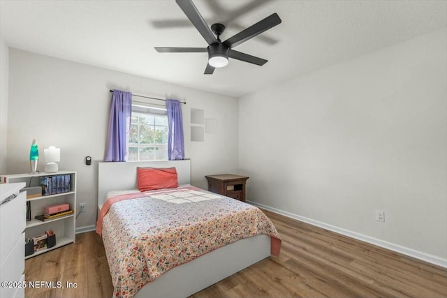 bedroom featuring baseboards, wood finished floors, and ceiling fan