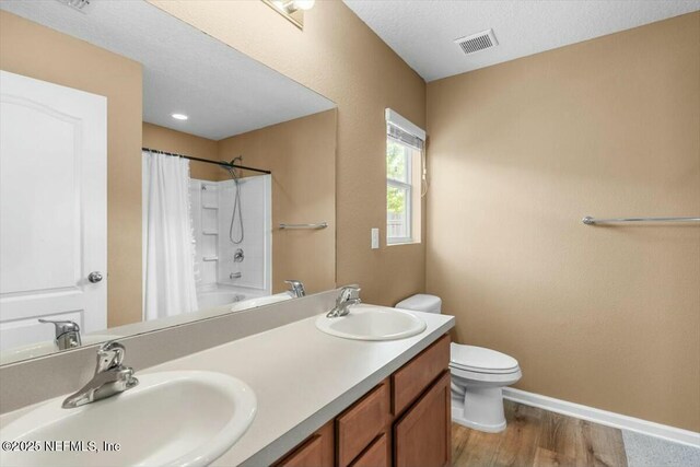 bathroom featuring toilet, wood finished floors, a sink, and visible vents
