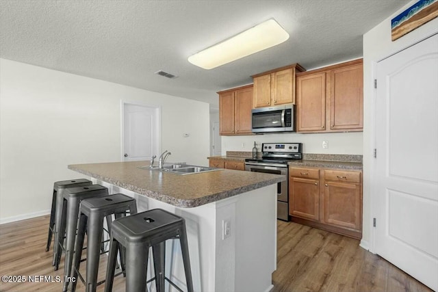 kitchen featuring appliances with stainless steel finishes, a sink, visible vents, and light wood-type flooring