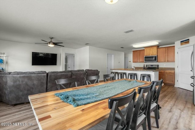 dining space featuring light wood finished floors, visible vents, and ceiling fan