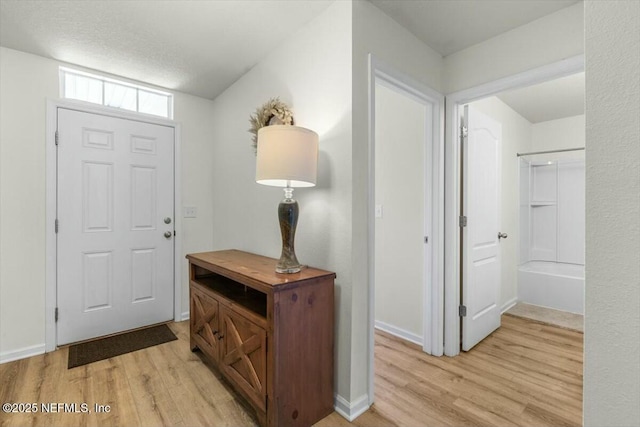 foyer entrance featuring light wood finished floors and baseboards