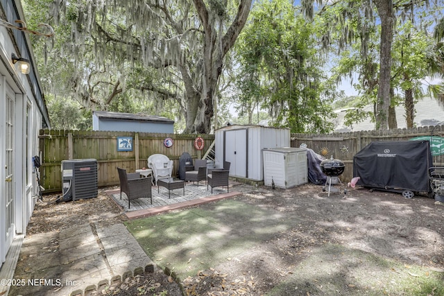 view of yard with cooling unit, an outbuilding, a fenced backyard, and a storage unit