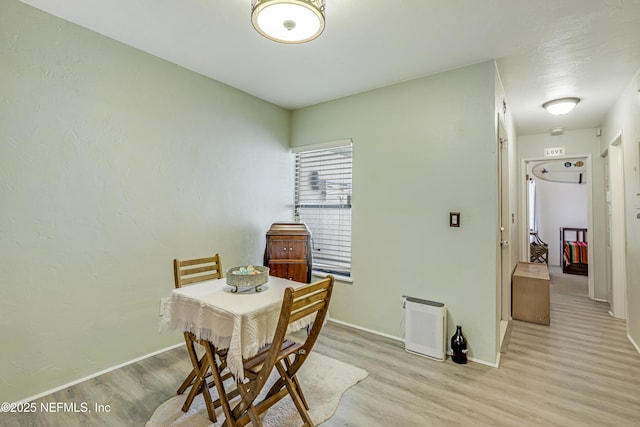dining space with baseboards and light wood-style flooring