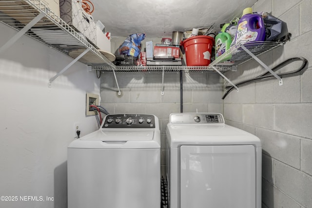 clothes washing area with laundry area, washer and dryer, and concrete block wall