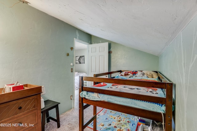 bedroom with a textured wall, carpet, vaulted ceiling, and a textured ceiling