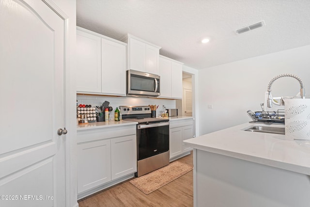 2916 Duck Hollow Ln, Green Cove Springs, FL 32043 - kitchen with stainless steel appliances, light wood-style flooring, tasteful backsplash, a sink, and light countertops