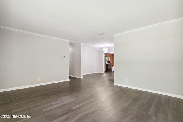 unfurnished room with a notable chandelier, dark wood-style floors, baseboards, and ornamental molding