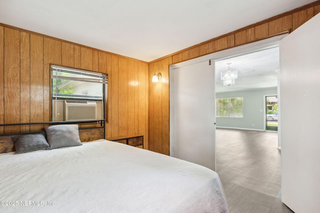 bedroom featuring wood walls, baseboards, cooling unit, and an inviting chandelier
