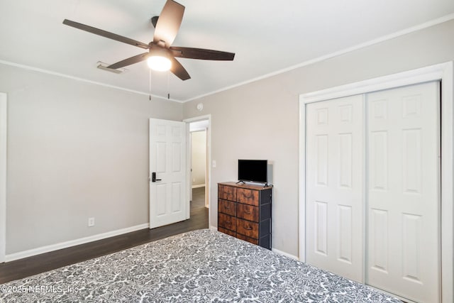 bedroom featuring a closet, baseboards, crown molding, visible vents, and dark wood finished floors