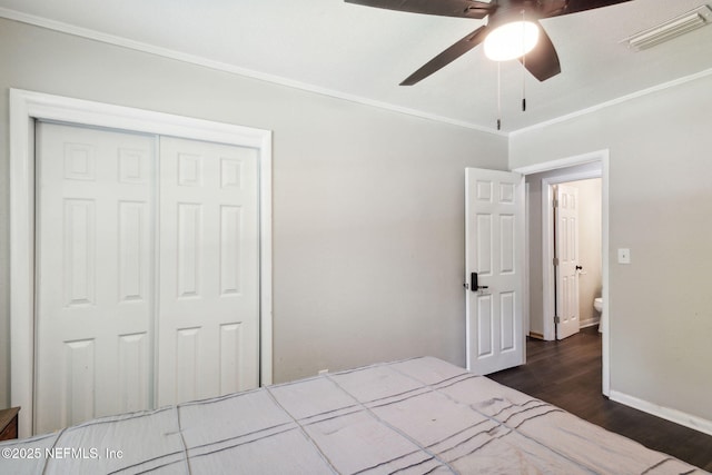 bedroom with a closet, visible vents, dark wood-style flooring, and ornamental molding