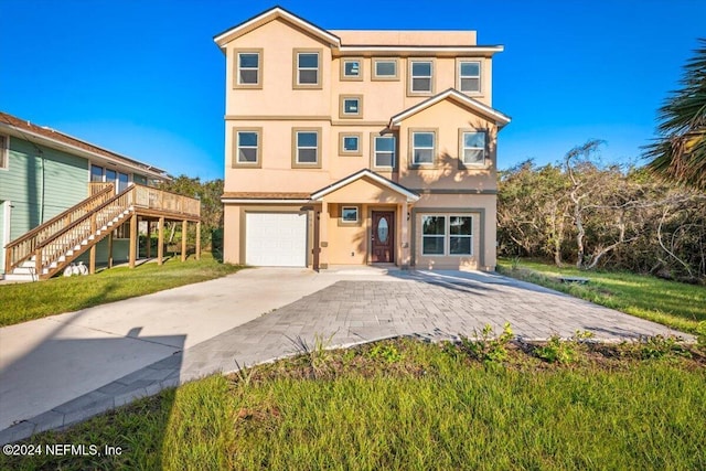 view of front of house with an attached garage, stucco siding, stairway, a front yard, and concrete driveway