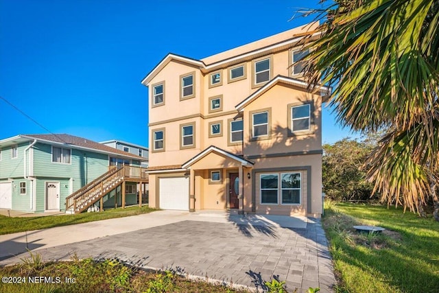view of front of home with an attached garage, a front lawn, stucco siding, stairway, and driveway