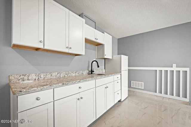 kitchen with a sink, marble finish floor, freestanding refrigerator, baseboards, and visible vents