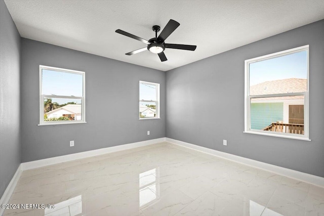 empty room with baseboards, a ceiling fan, and marble finish floor