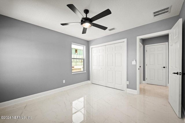 unfurnished bedroom with ceiling fan, marble finish floor, baseboards, visible vents, and a closet