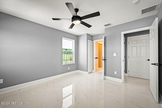 unfurnished bedroom featuring visible vents, a textured ceiling, marble finish floor, and baseboards