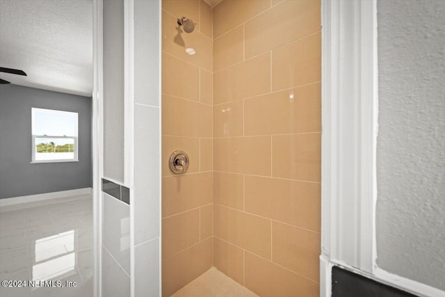 full bath featuring baseboards and a tile shower