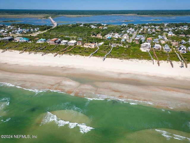drone / aerial view featuring a water view, a residential view, and a beach view