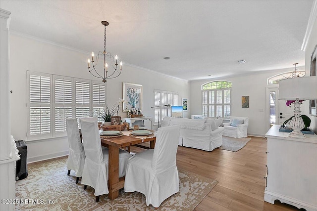 dining area with ornamental molding, baseboards, a notable chandelier, and light wood-type flooring