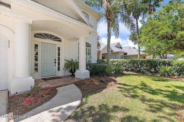 property entrance featuring a lawn, a porch, and stucco siding