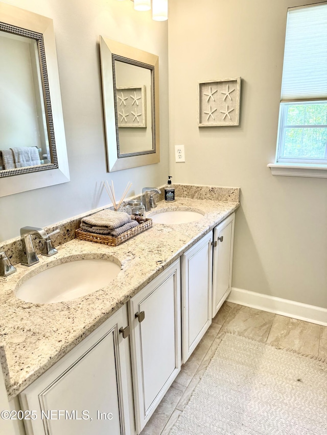 full bath featuring baseboards, a sink, marble finish floor, and double vanity