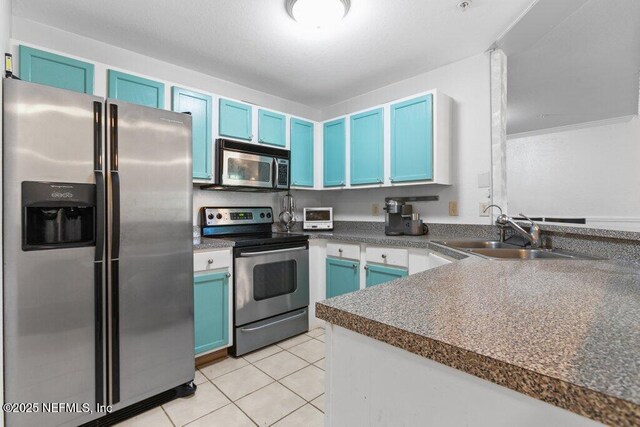 7800 Point Meadows Dr Unit 1035, Jacksonville, FL 32256 - kitchen with appliances with stainless steel finishes, blue cabinetry, a sink, light tile patterned floors, and dark countertops