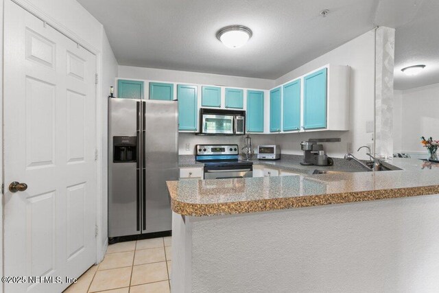 7800 Point Meadows Dr Unit 1035, Jacksonville, FL 32256 - kitchen featuring stainless steel appliances, blue cabinetry, a sink, a peninsula, and light tile patterned floors