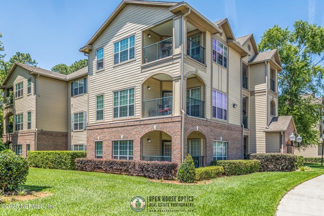 7800 Point Meadows Dr Unit 1035, Jacksonville, FL 32256 - view of front of property featuring a balcony, brick siding, and a front lawn