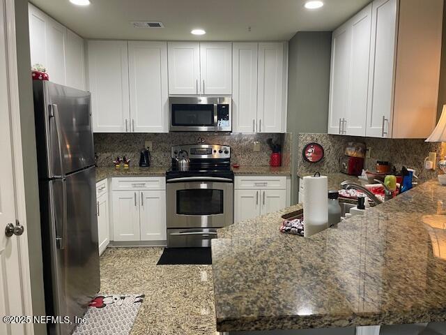 400 E Bay St Unit 502, Jacksonville, FL 32202 - kitchen with stainless steel appliances, stone counters, visible vents, and white cabinetry