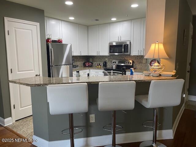 400 E Bay St Unit 502, Jacksonville, FL 32202 - kitchen with stainless steel appliances, a peninsula, light wood-style flooring, baseboards, and light stone countertops
