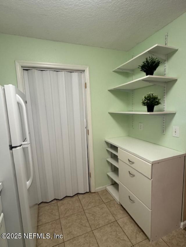 7701 Timberlin Park Blvd Unit 531, Jacksonville, FL 32256 - kitchen featuring open shelves, freestanding refrigerator, light tile patterned floors, a textured ceiling, and light countertops