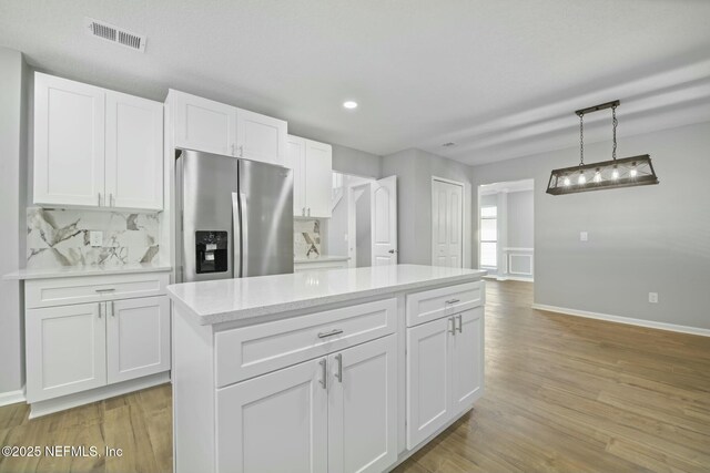 3399 Shauna Oaks Cir, Jacksonville, FL 32277 - kitchen with white cabinets, baseboards, visible vents, backsplash, and stainless steel refrigerator with ice dispenser