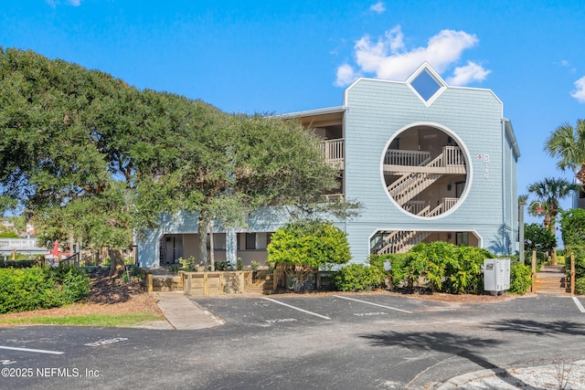 view of property featuring uncovered parking and stairway